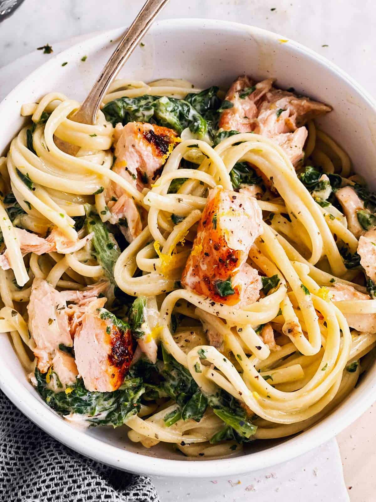 white bowl with creamy salmon pasta and spinach