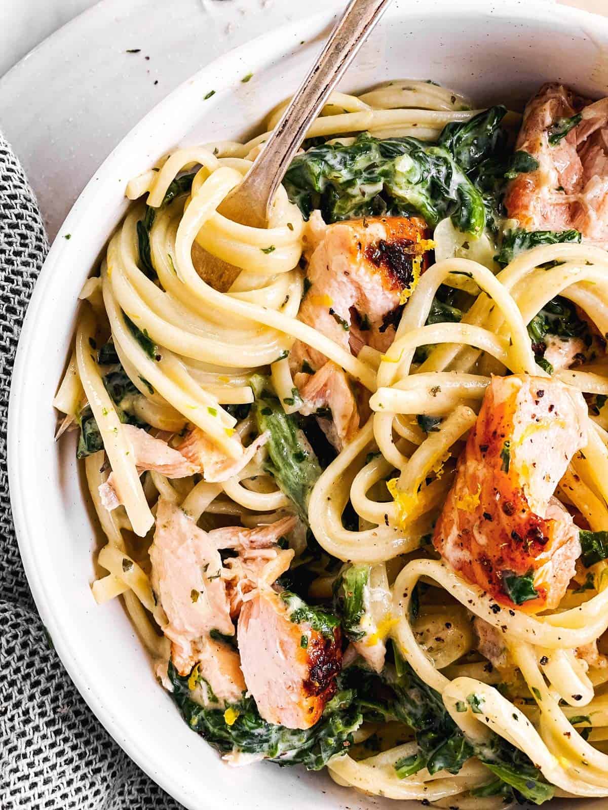 close up photo of creamy salmon pasta in white bowl