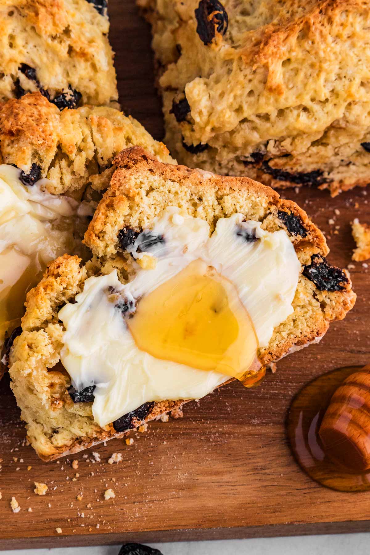 frontal view of sliced soda bread spread with butter and honey