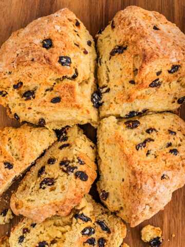 overhead view of Irish soda bread with raisins on wooden board with one quarter removed