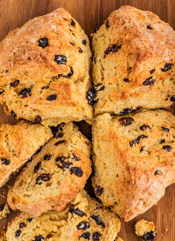 overhead view of Irish soda bread with raisins on wooden board with one quarter removed