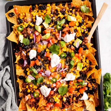 overhead view of nachos on dark colored sheet pan