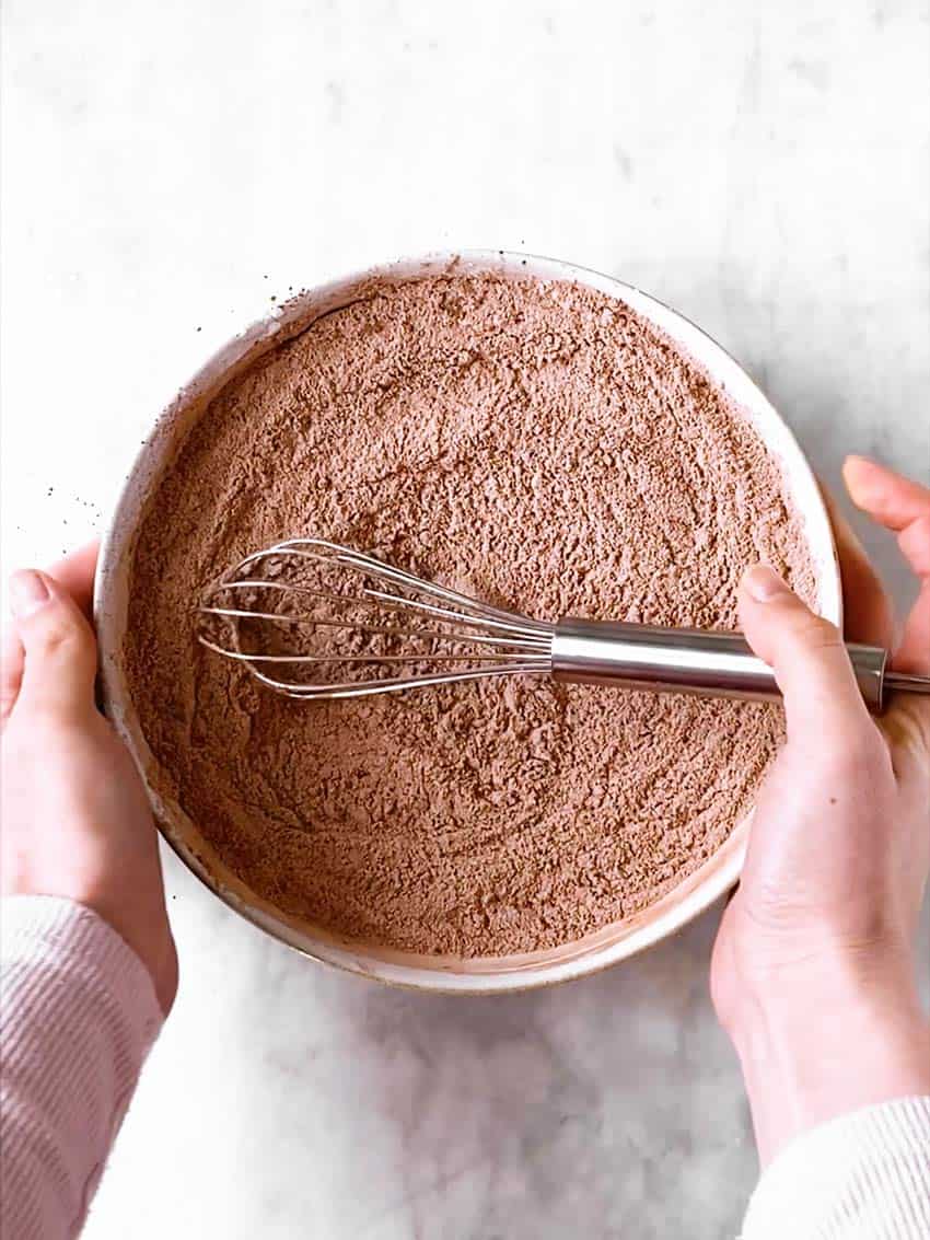 female hands holding bowl with combined dry ingredients for cupcakes