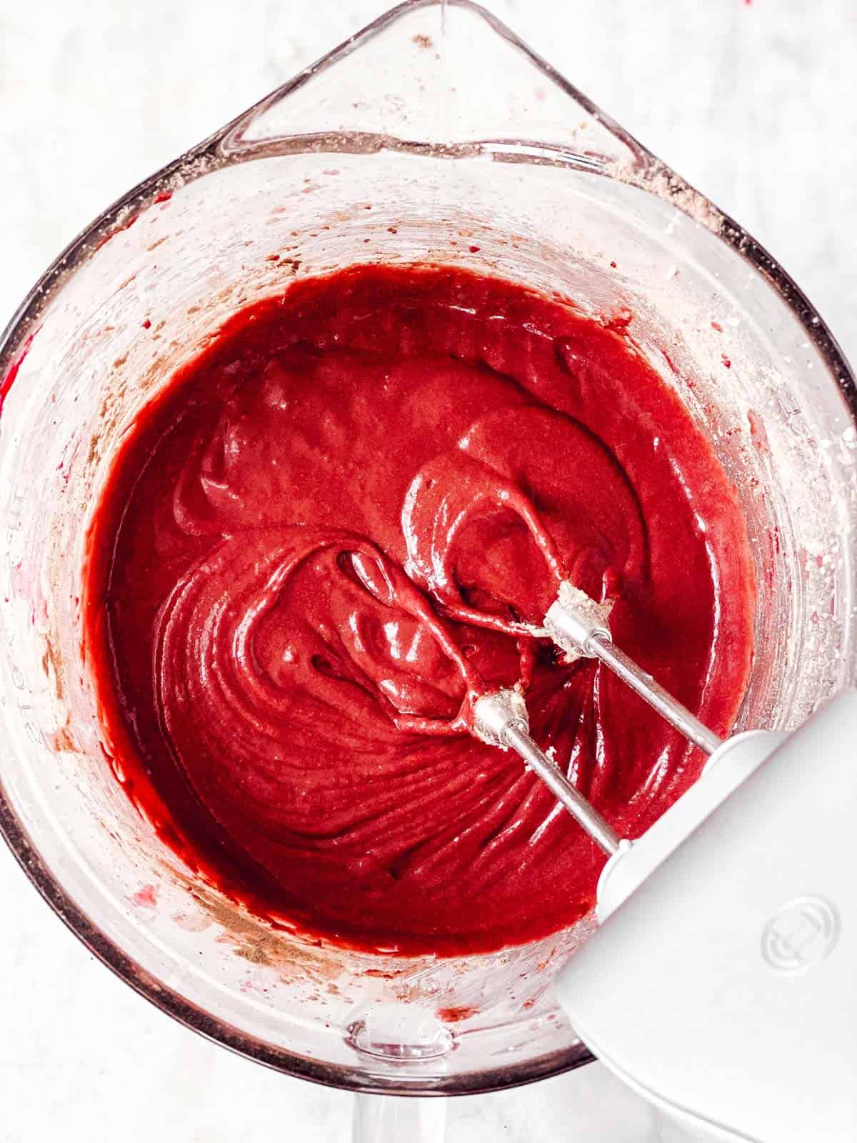 red velvet cupcake batter in glass bowl with beaters from mixer