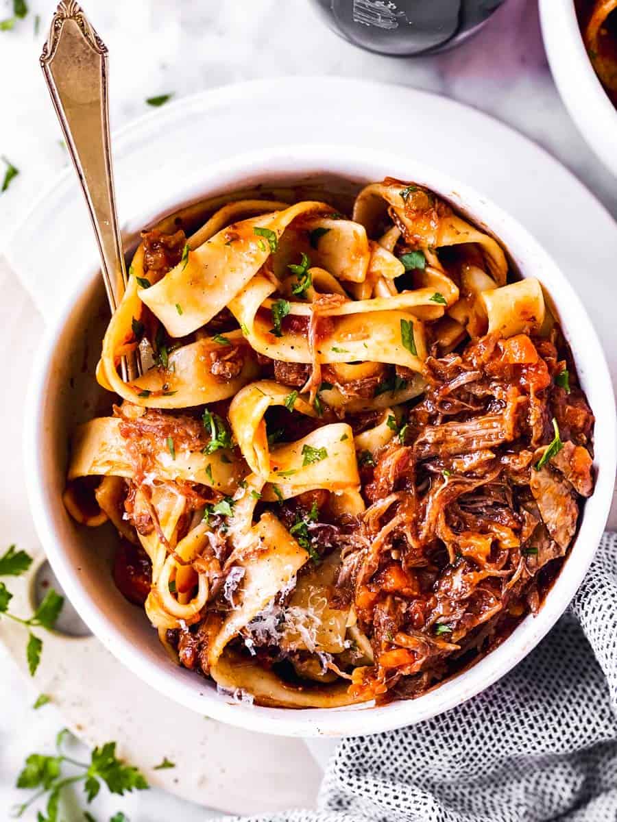 overhead view of white bowl with pappardelle and short rib ragù