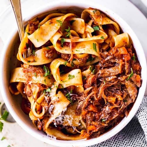 overhead view of white bowl with pappardelle and short rib ragù