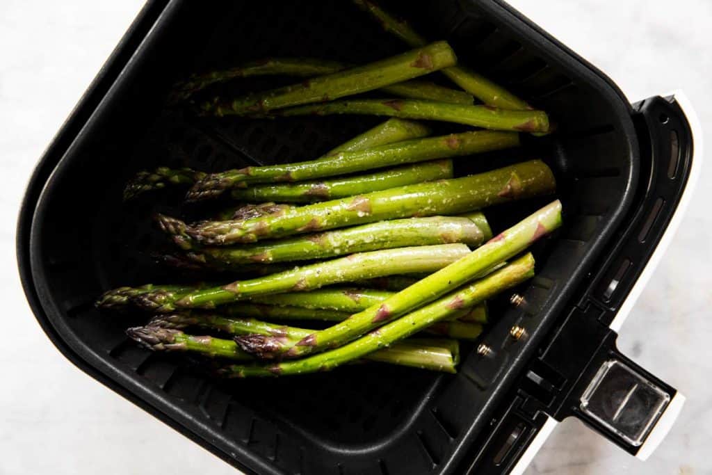 raw asparagus in air fryer basket