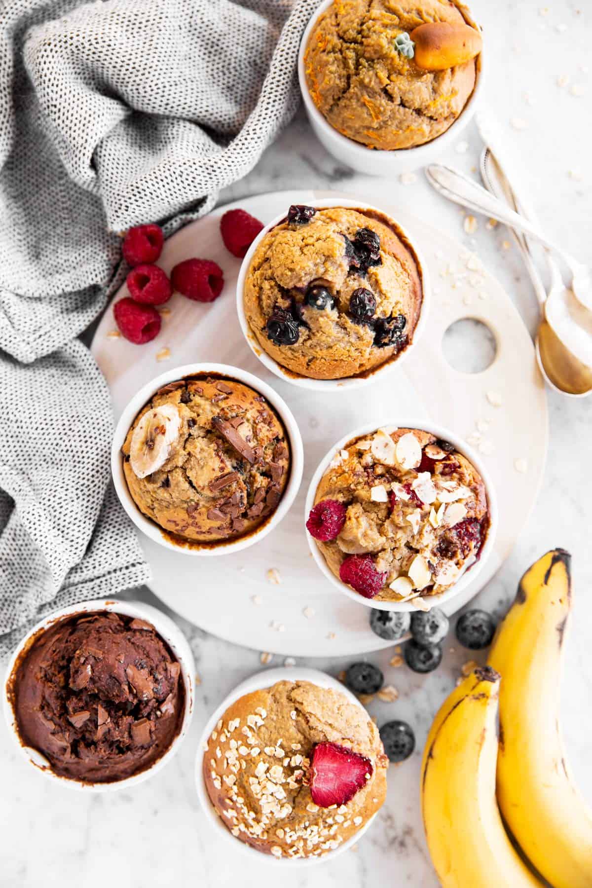 six ramekins with baked oats on a table with fresh fruit