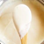 close up photo of béchamel sauce on wooden spoon