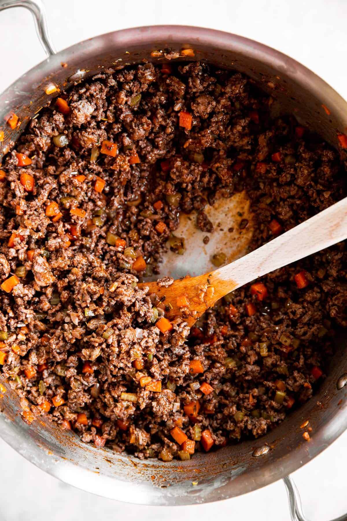 beef and vegetables for Bolognese sauce with red wine in stainless steel pan