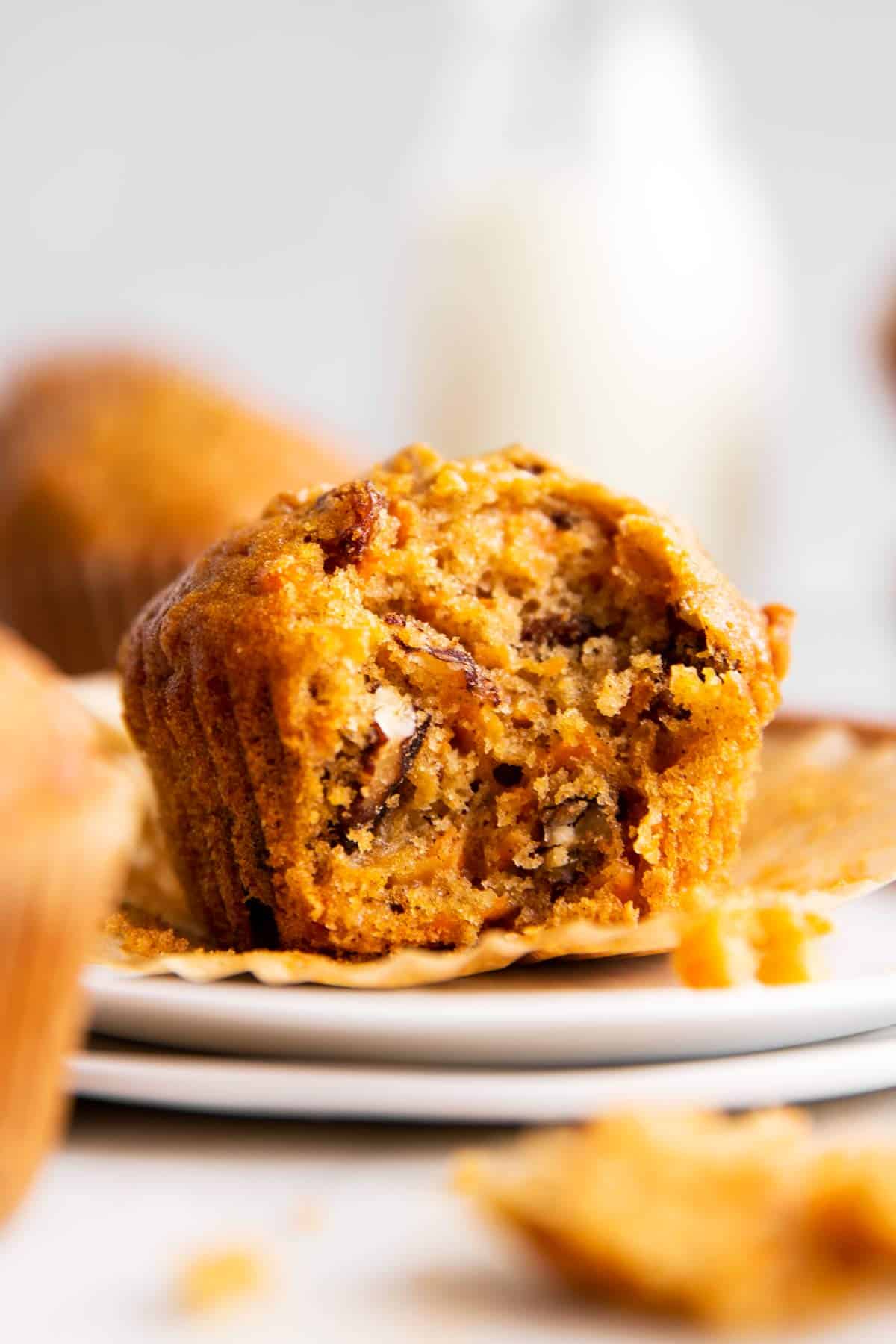 carrot muffin with bite taken out on top of two stacked white plates