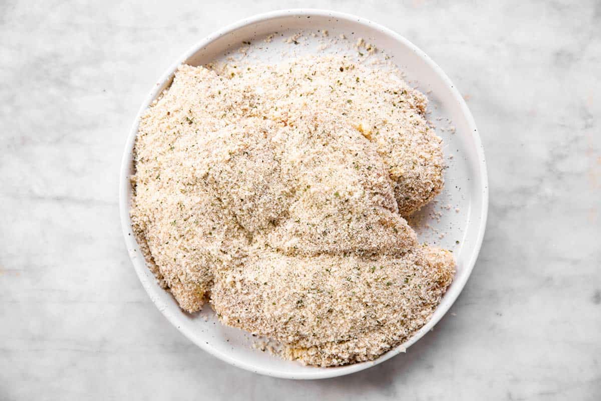 four bread chicken breasts on white plate