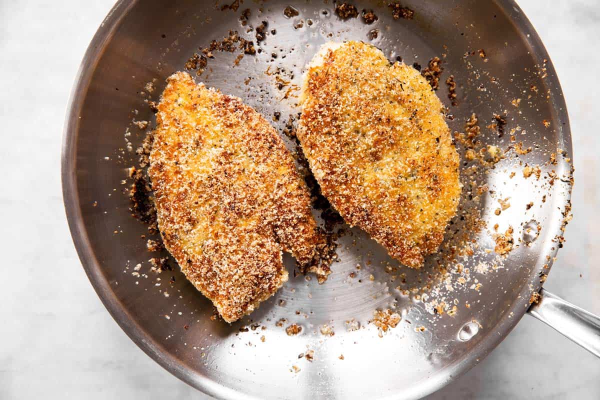 two breaded chicken breasts browned in skillet
