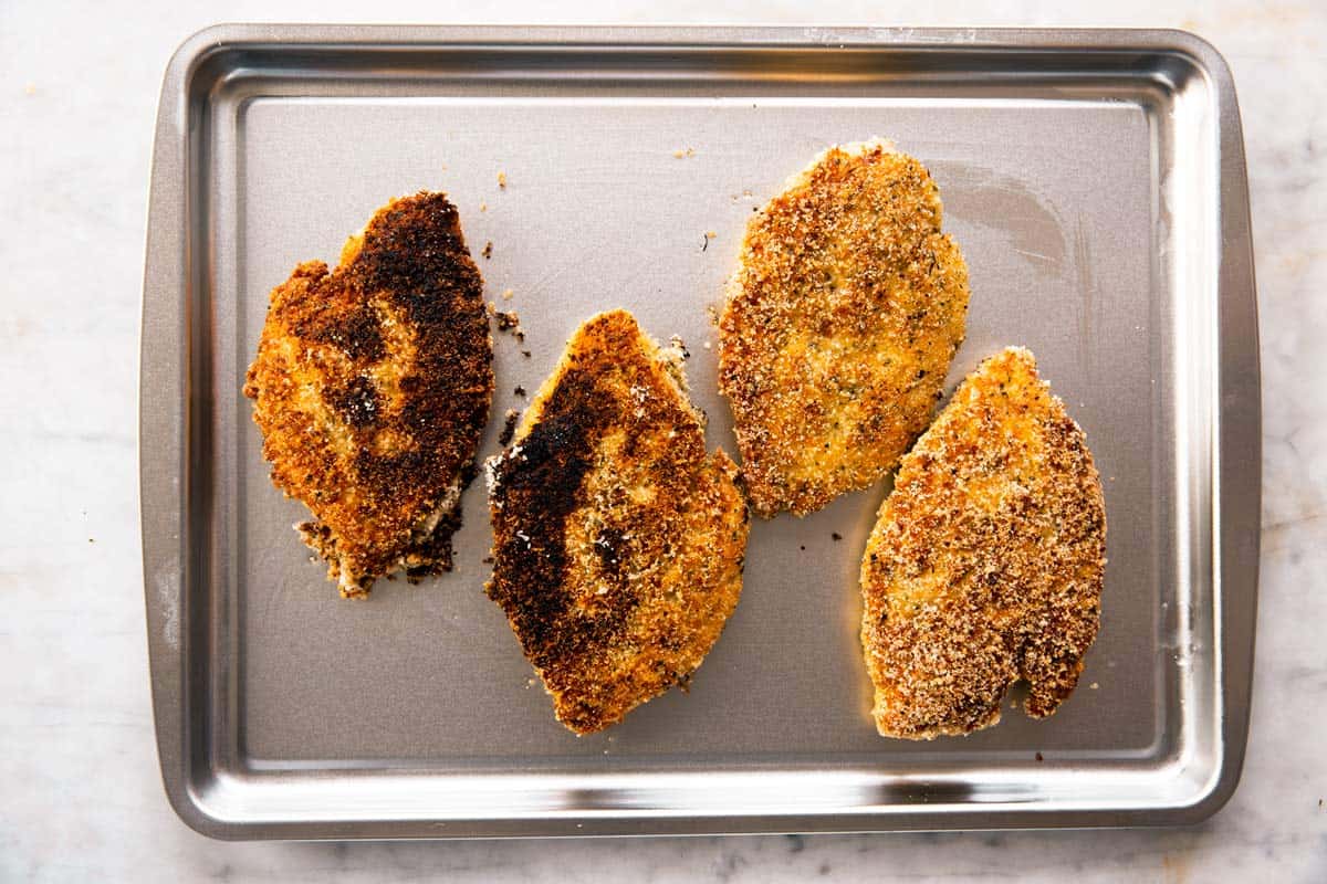 four breaded chicken breasts on sheet pan