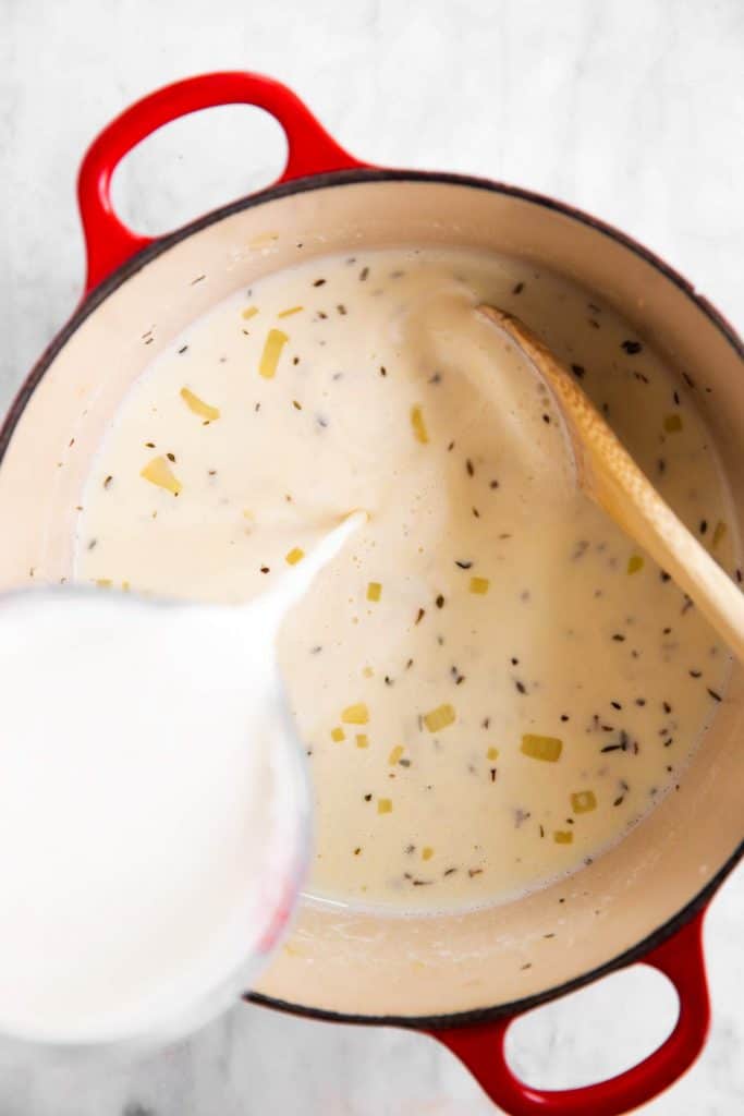 pouring milk over roux in Dutch oven