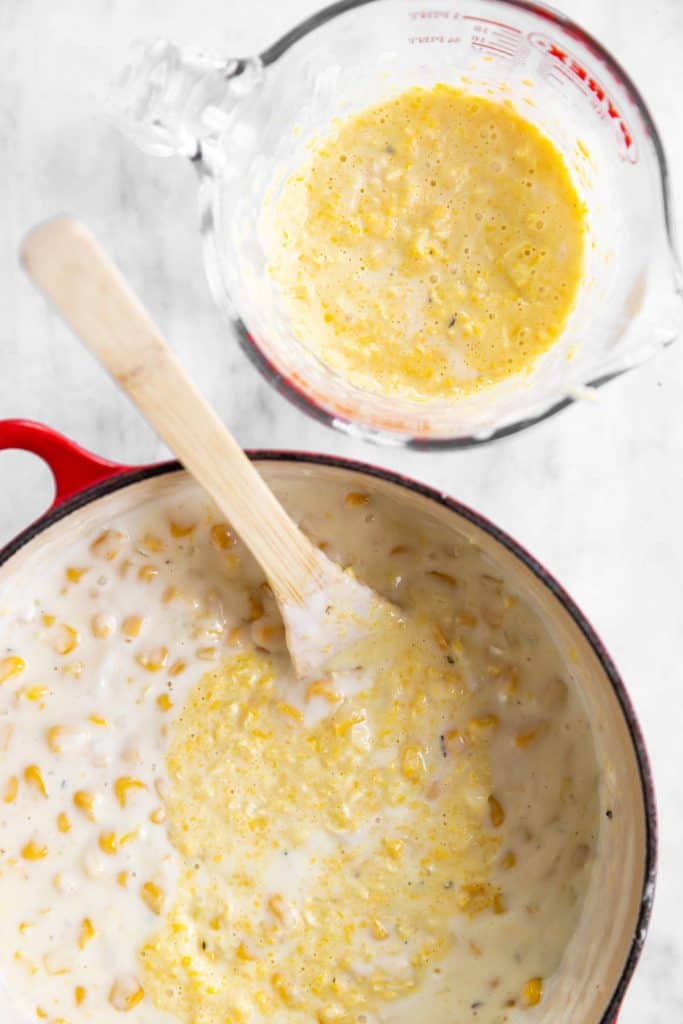 Dutch oven with creamed corn and glass measuring jug with blended creamed corn next to each other
