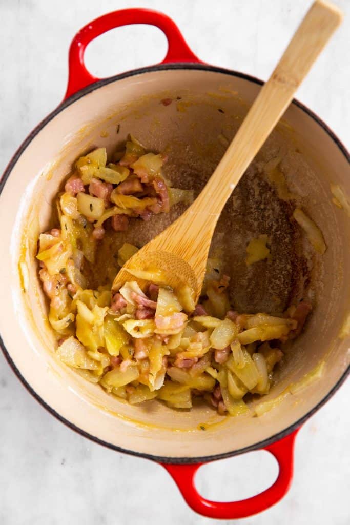 cast iron pot with sautéed onion and bacon and flour stirred in
