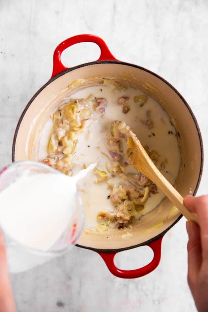 pouring milk into pot with roux