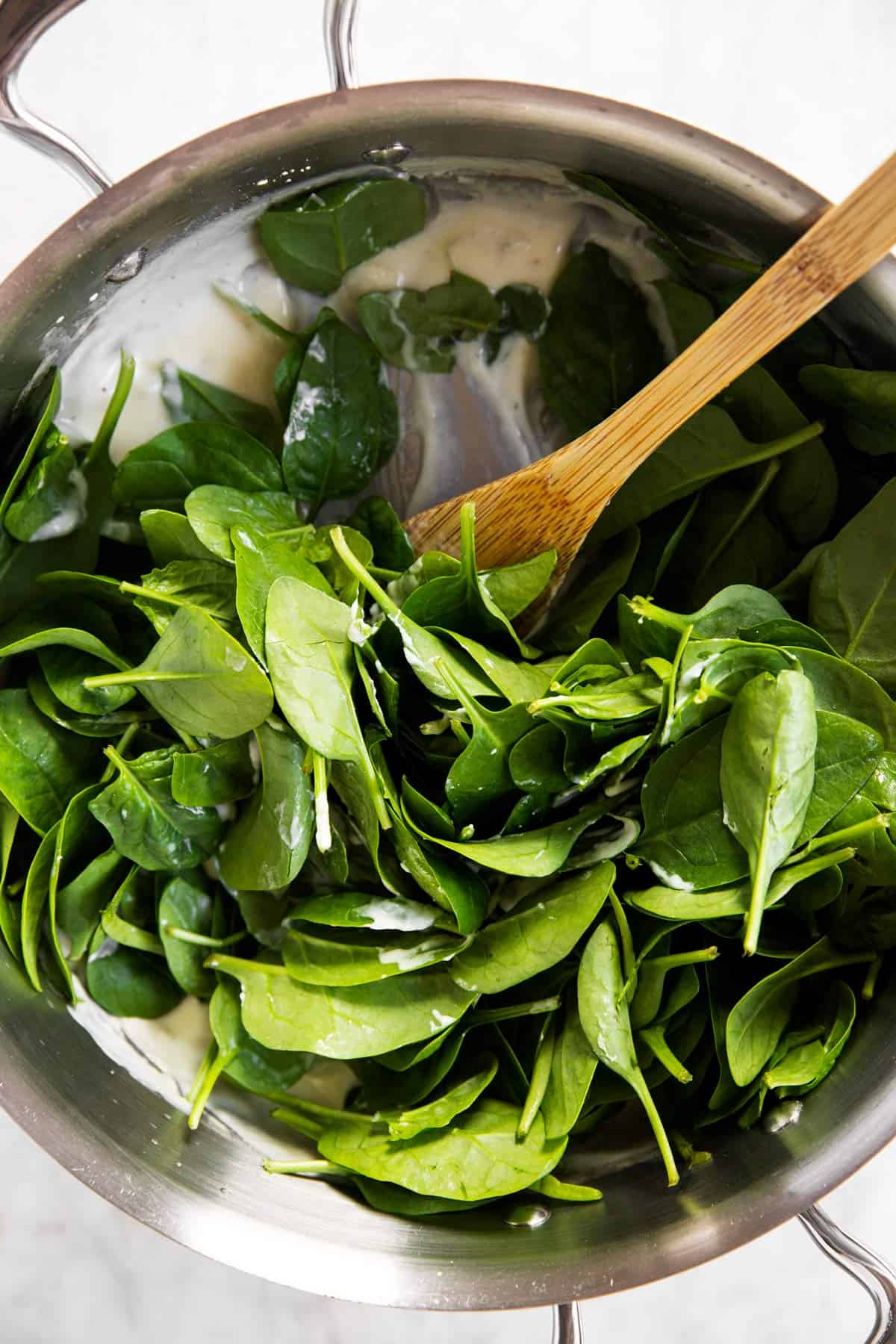 raw baby spinach in pan with Béchamel sauce