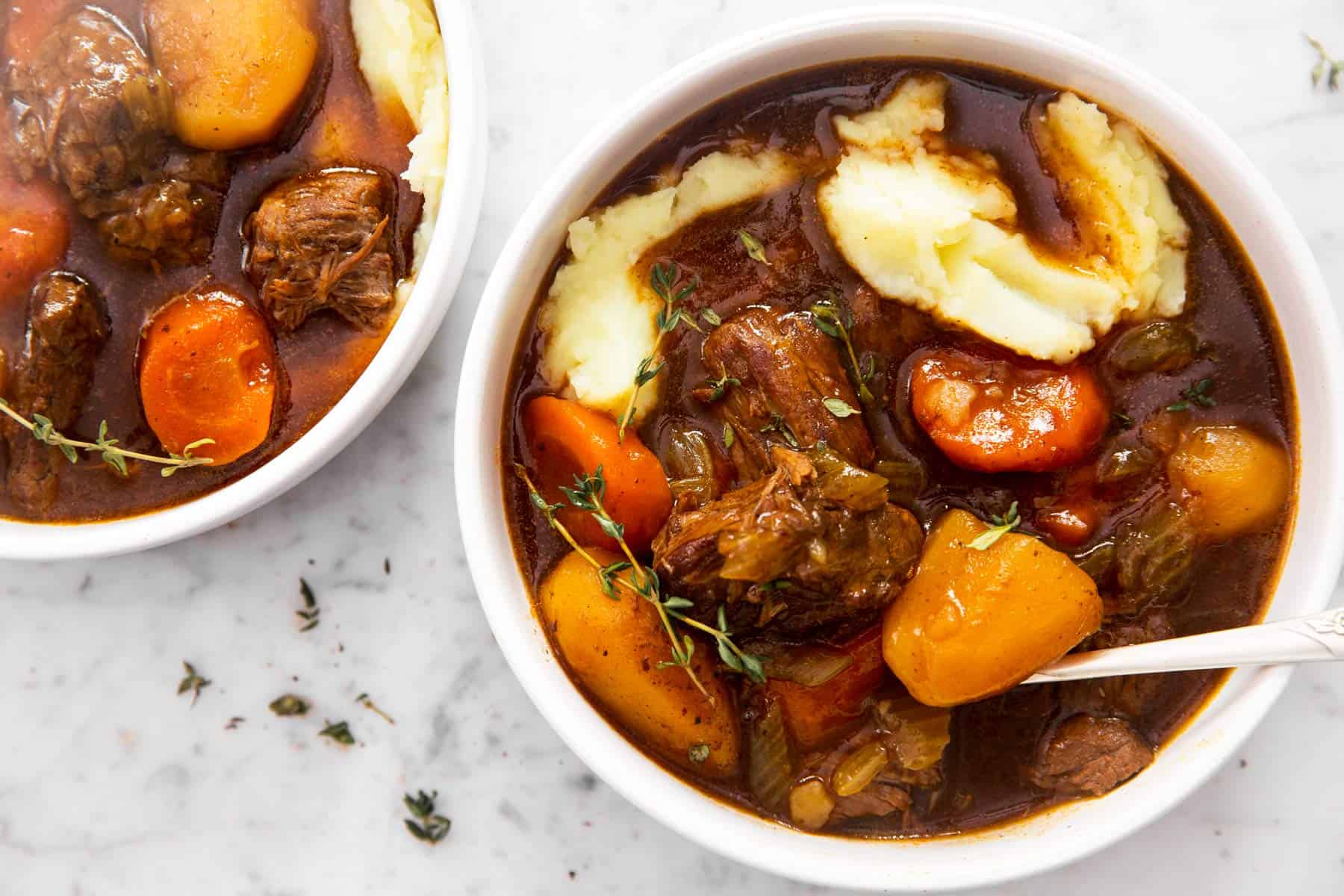 two bowls with irish beef stew on marble surface