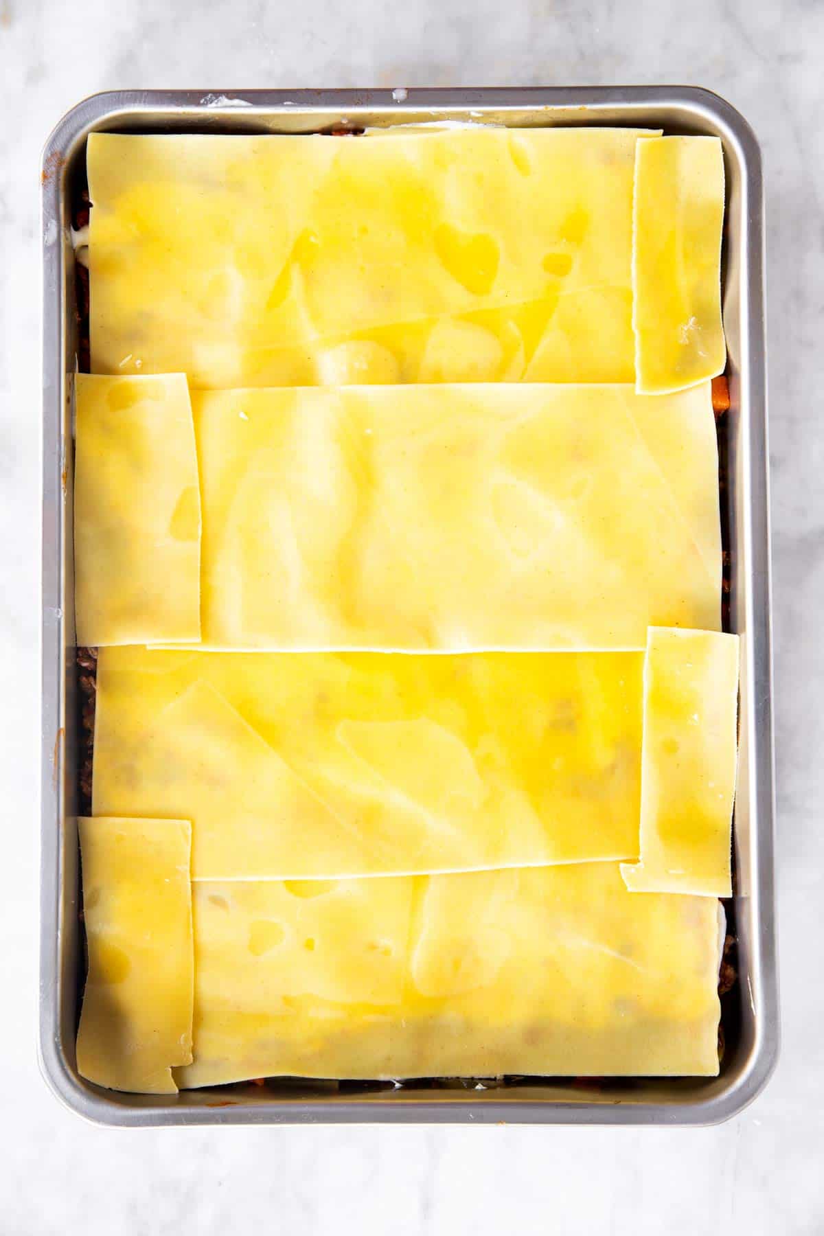 casserole dish with third layer of lasagna noodles