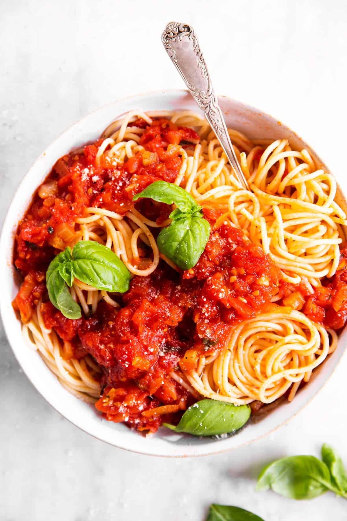 overhead view of plate of spaghetti with marinara sauce and fresh basil