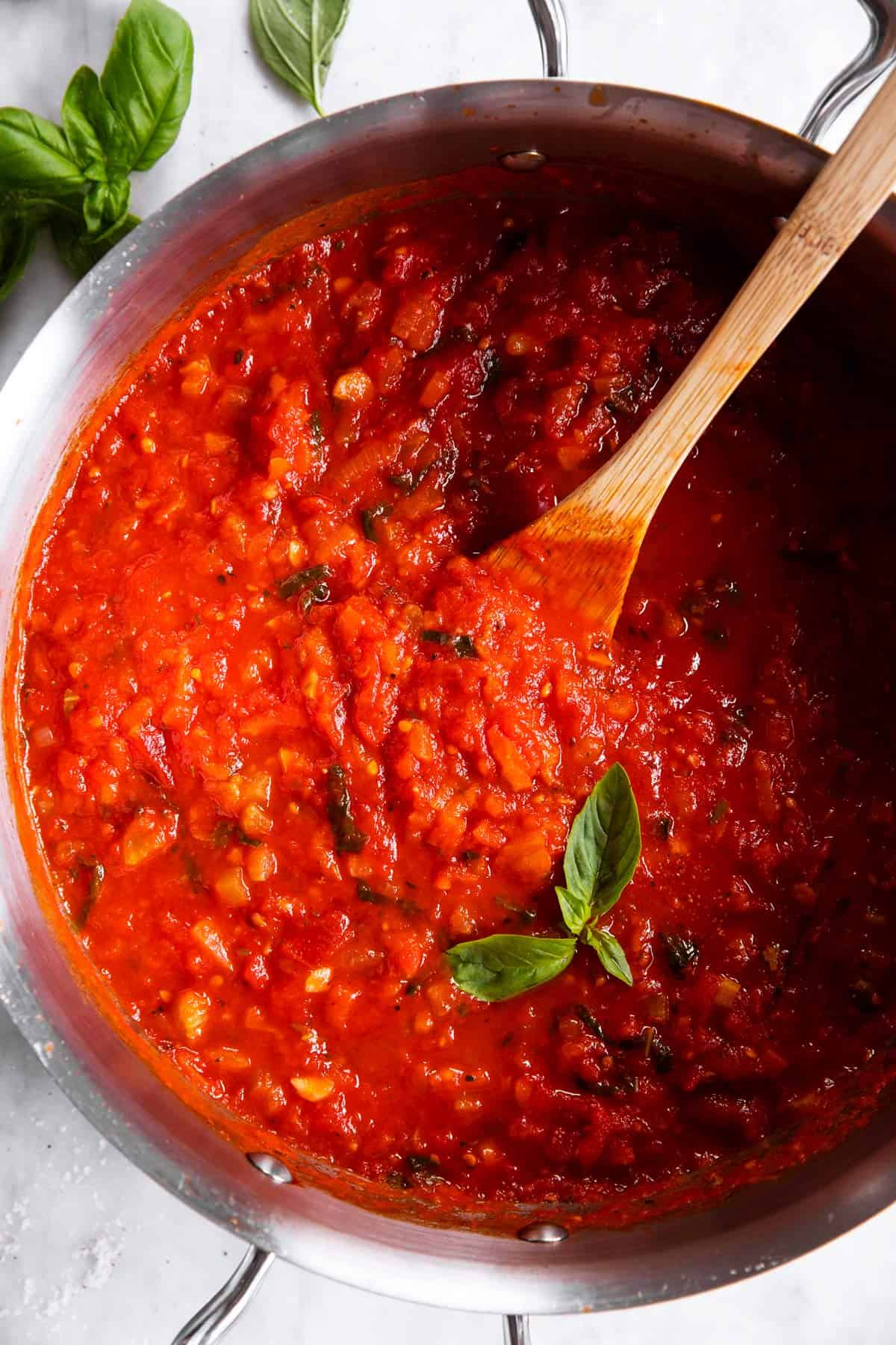 overhead view of marinara sauce in pan with wooden spoon