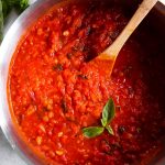 overhead view of marinara sauce in pan with wooden spoon