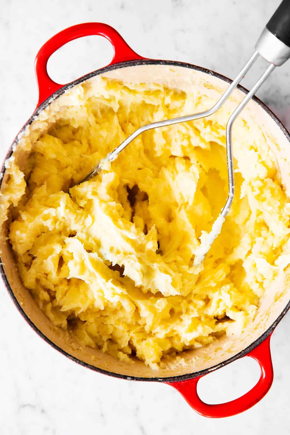 potato masher in pot with mashed potatoes