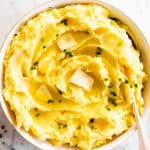 mashed potatoes in white bowl with butter and chives