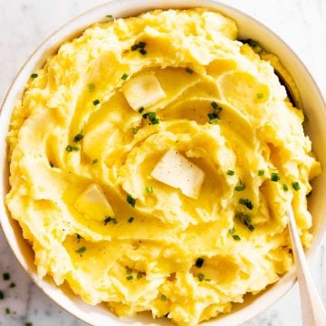 mashed potatoes in white bowl with butter and chives