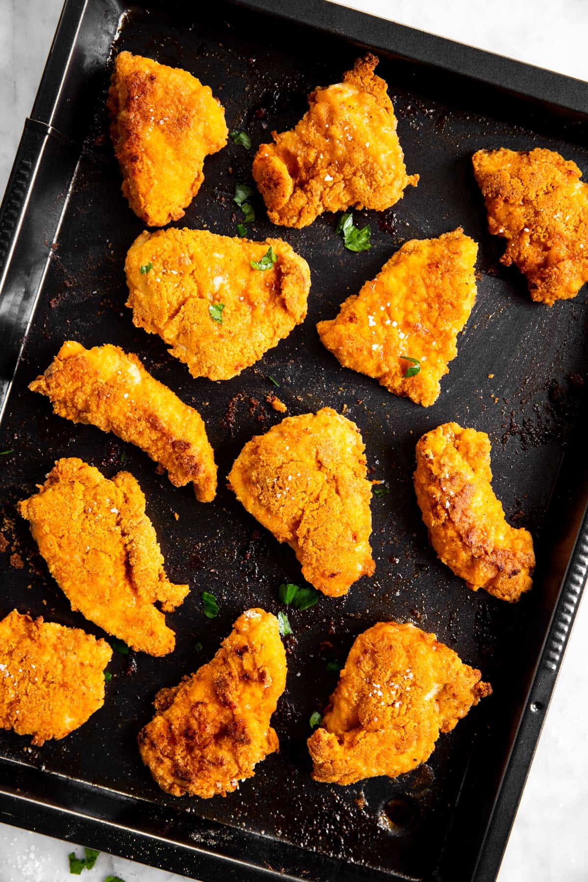 overhead view of black pan with oven fried chicken