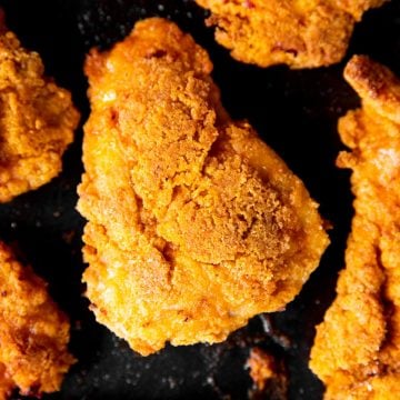 overhead close up photo of a piece of oven fried chicken on a black sheet pan