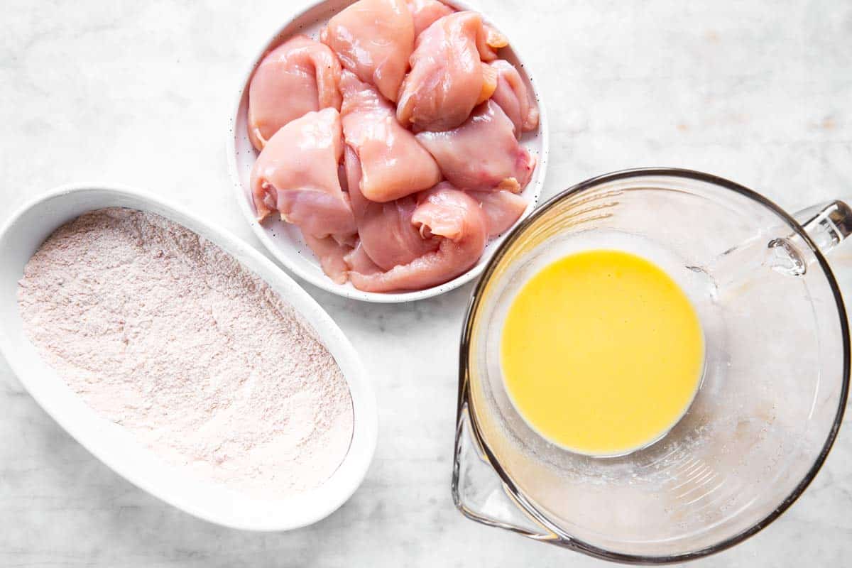 breading mix, egg wash and chicken on plates and in bowls