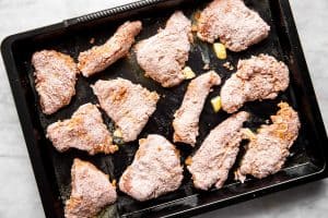 unbaked breaded chicken on dark pan