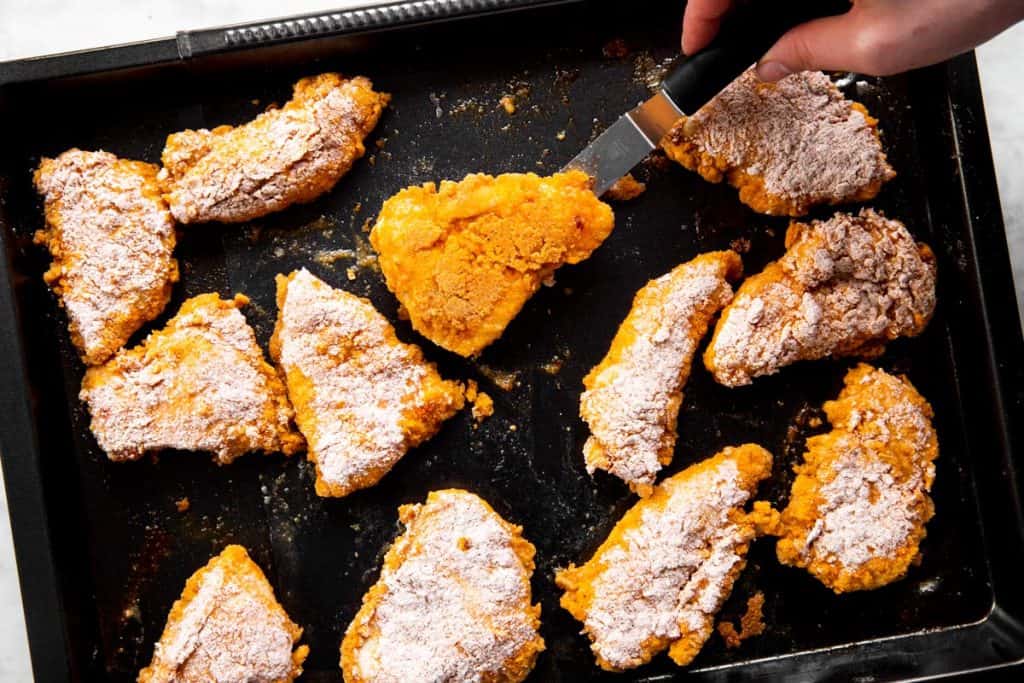 flipping oven fried chicken on black pan