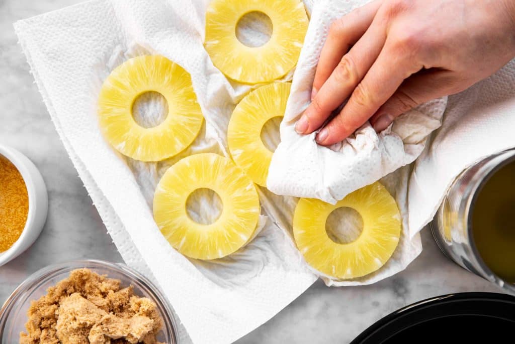 female hand patting dry pineapple rings