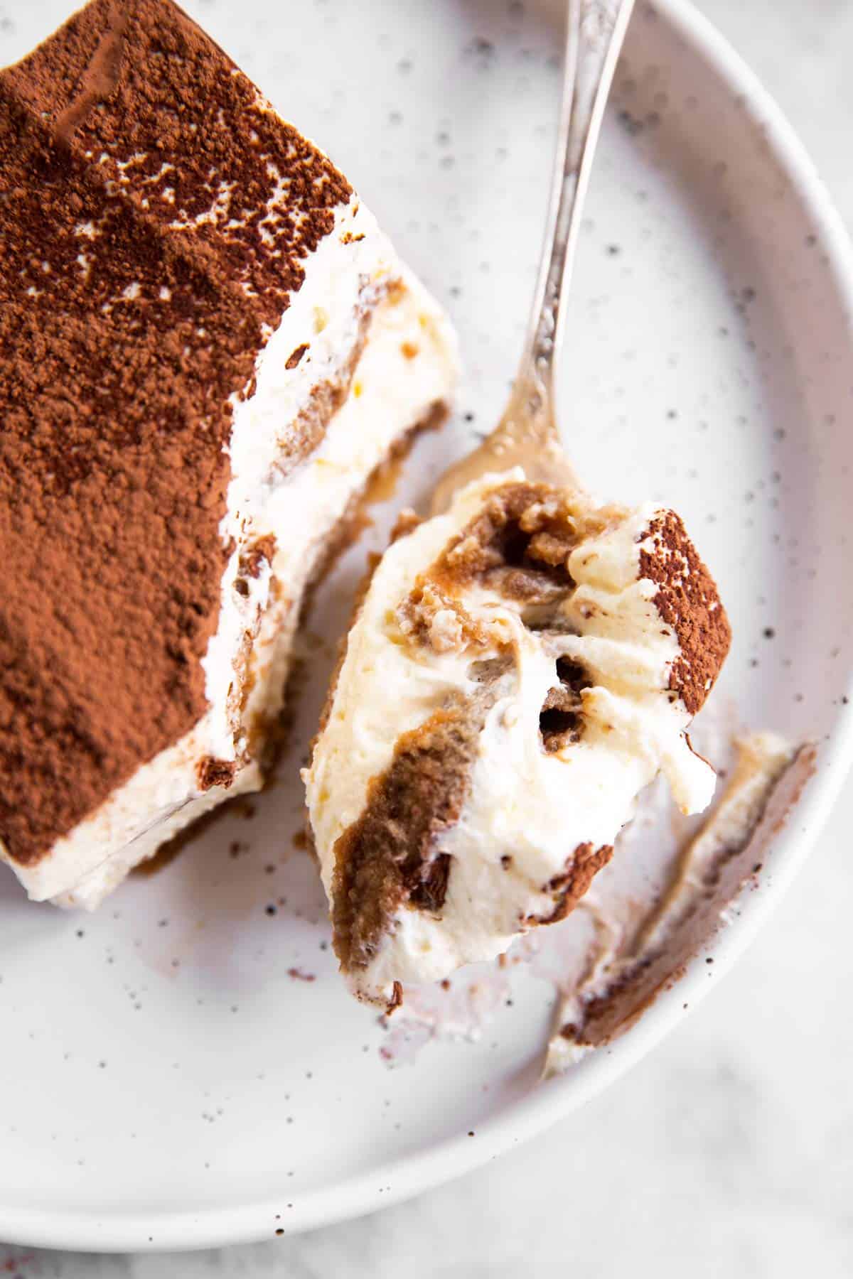 overhead view of slice of Tiramisu with fork having bite taken out on plate