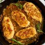 Serving honey mustard chicken from a cast iron skillet with fresh rosemary.