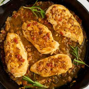 Serving honey mustard chicken from a cast iron skillet with fresh rosemary.