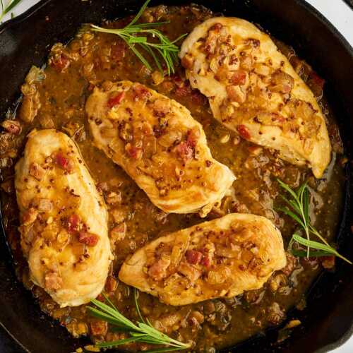 Serving honey mustard chicken from a cast iron skillet with fresh rosemary.