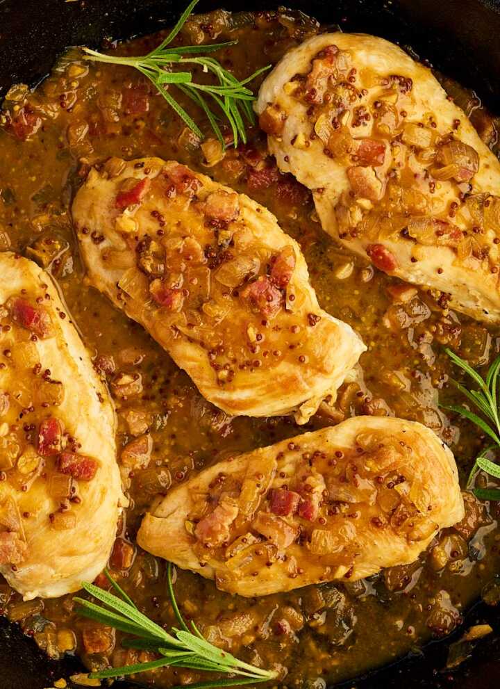 Serving honey mustard chicken from a cast iron skillet with fresh rosemary.