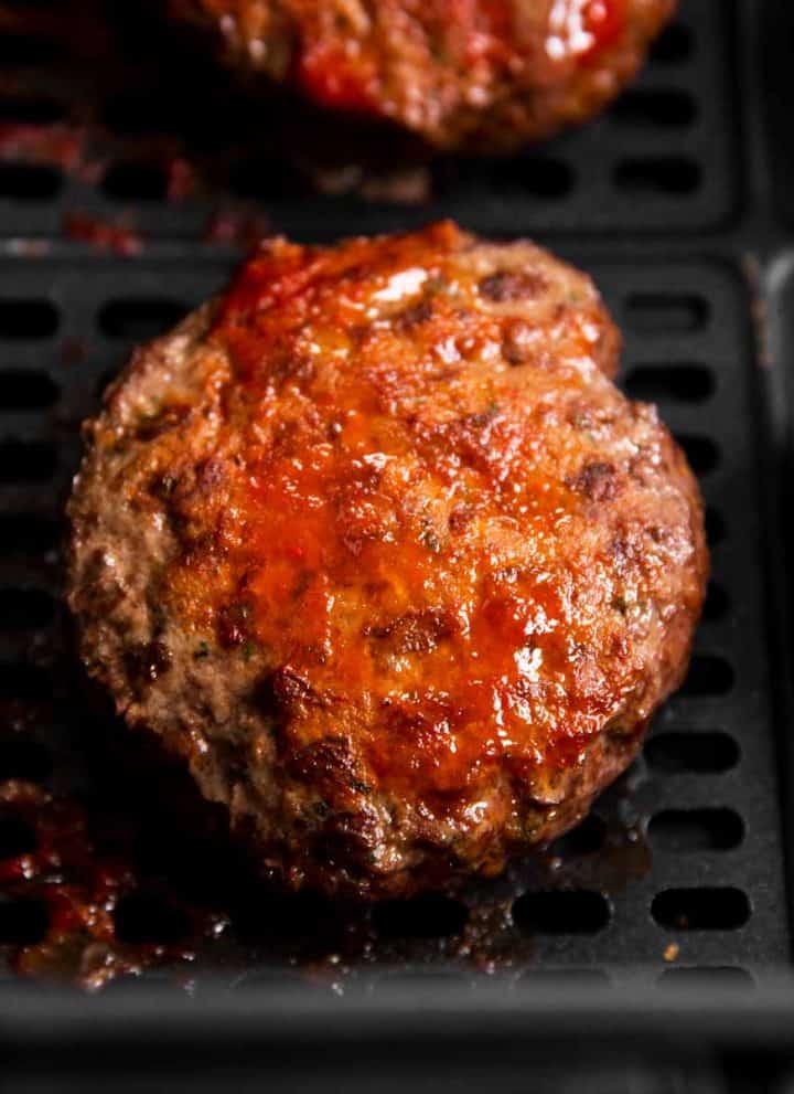close up photo of air fryer burger patty in air fryer basket