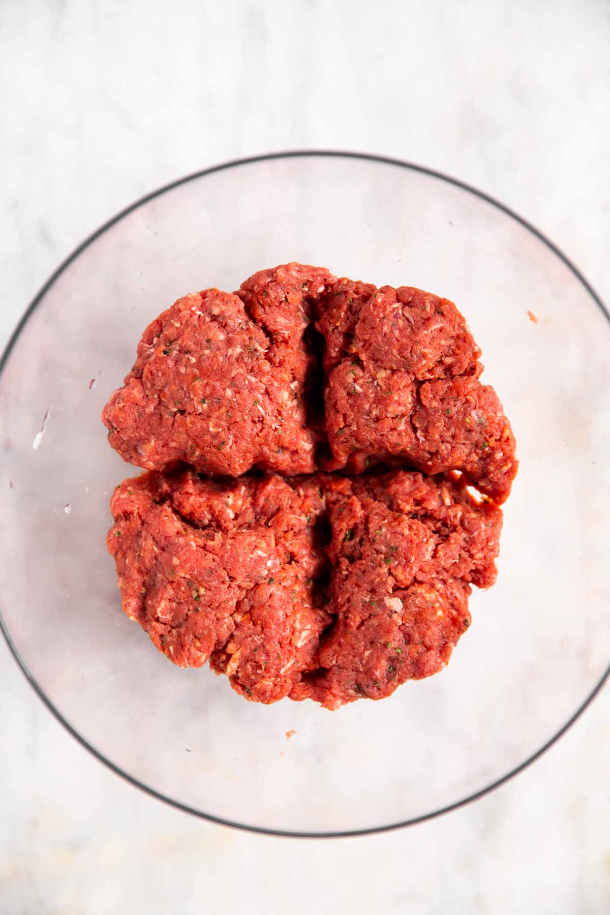 burger patty mixture in glass bowl divided into four parts