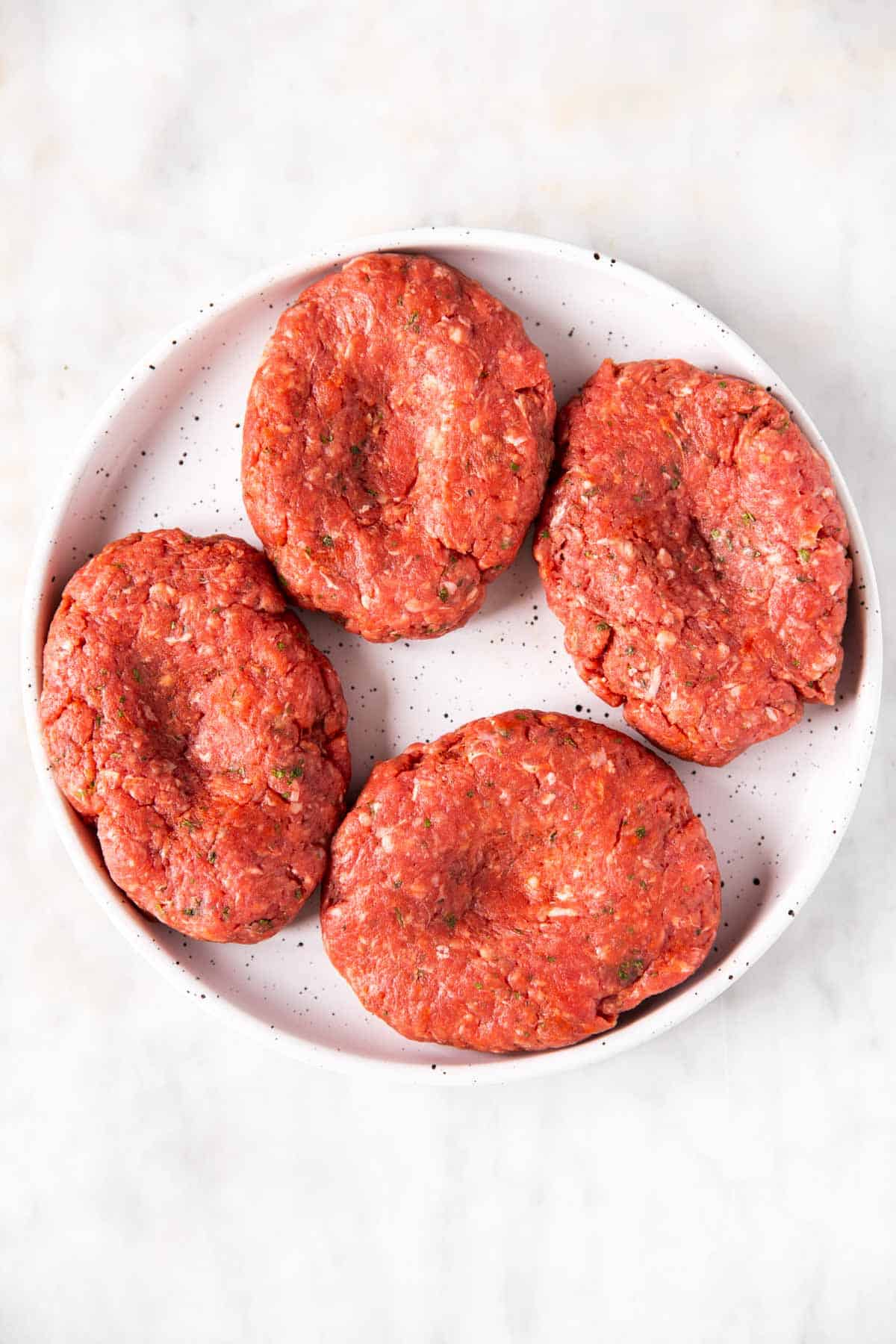 four shaped burger patties on white plate