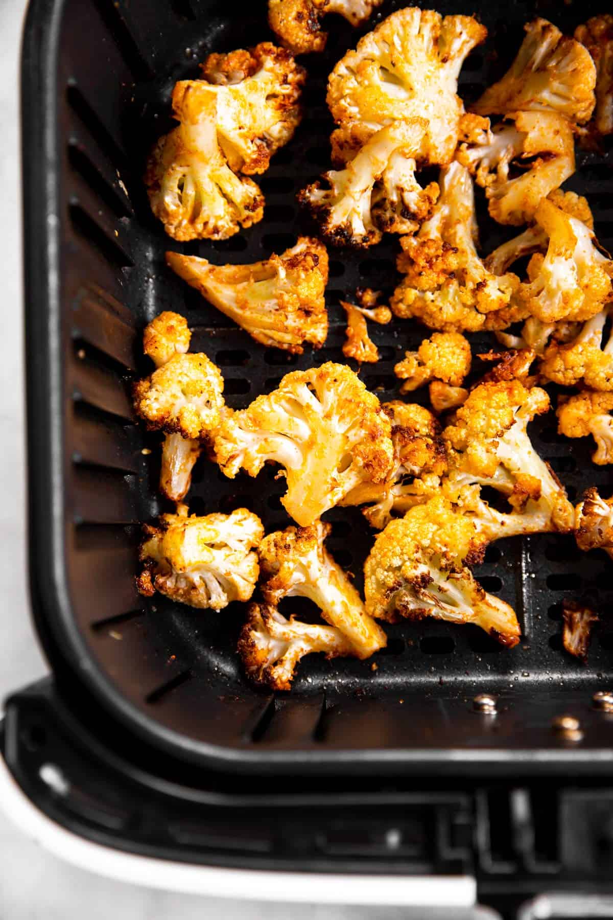 overhead view of roasted cauliflower in air fryer basket