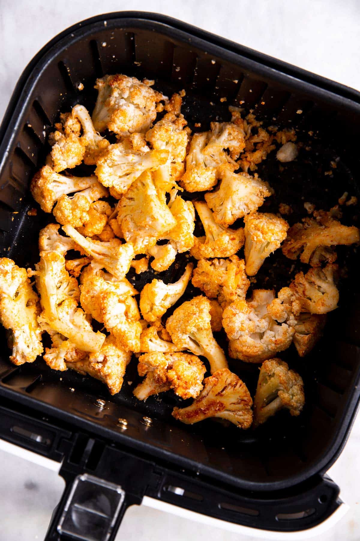 raw seasoned cauliflower in air fryer basket