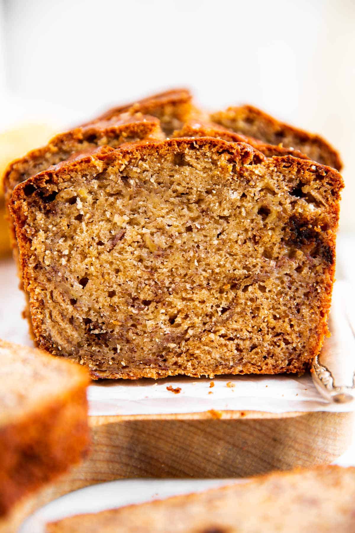 frontal view of sliced banana bread on parchment paper sitting on wooden board