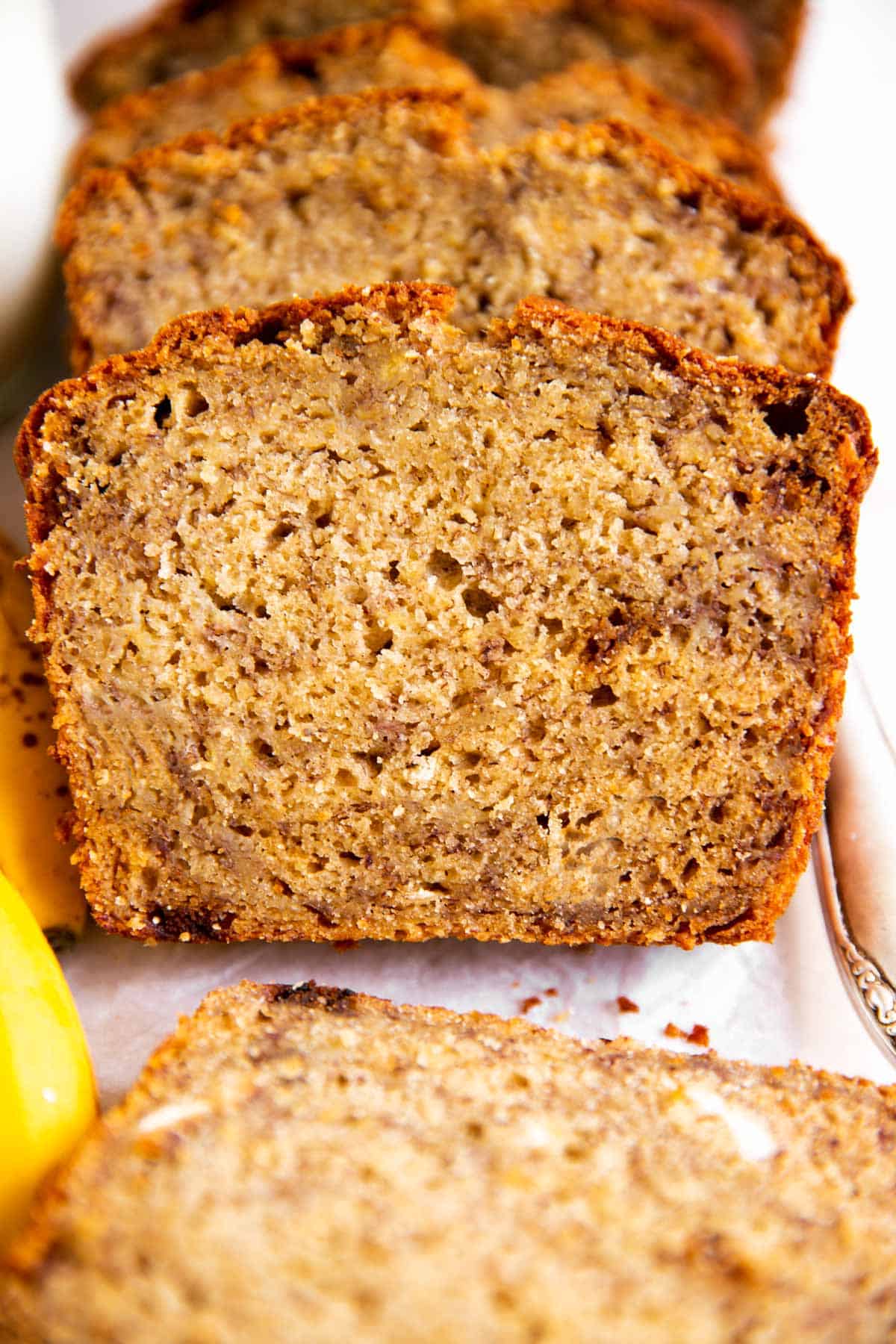 frontal view of sliced banana bread on white parchment paper