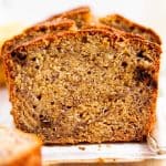 frontal view of sliced banana bread on parchment paper sitting on wooden board